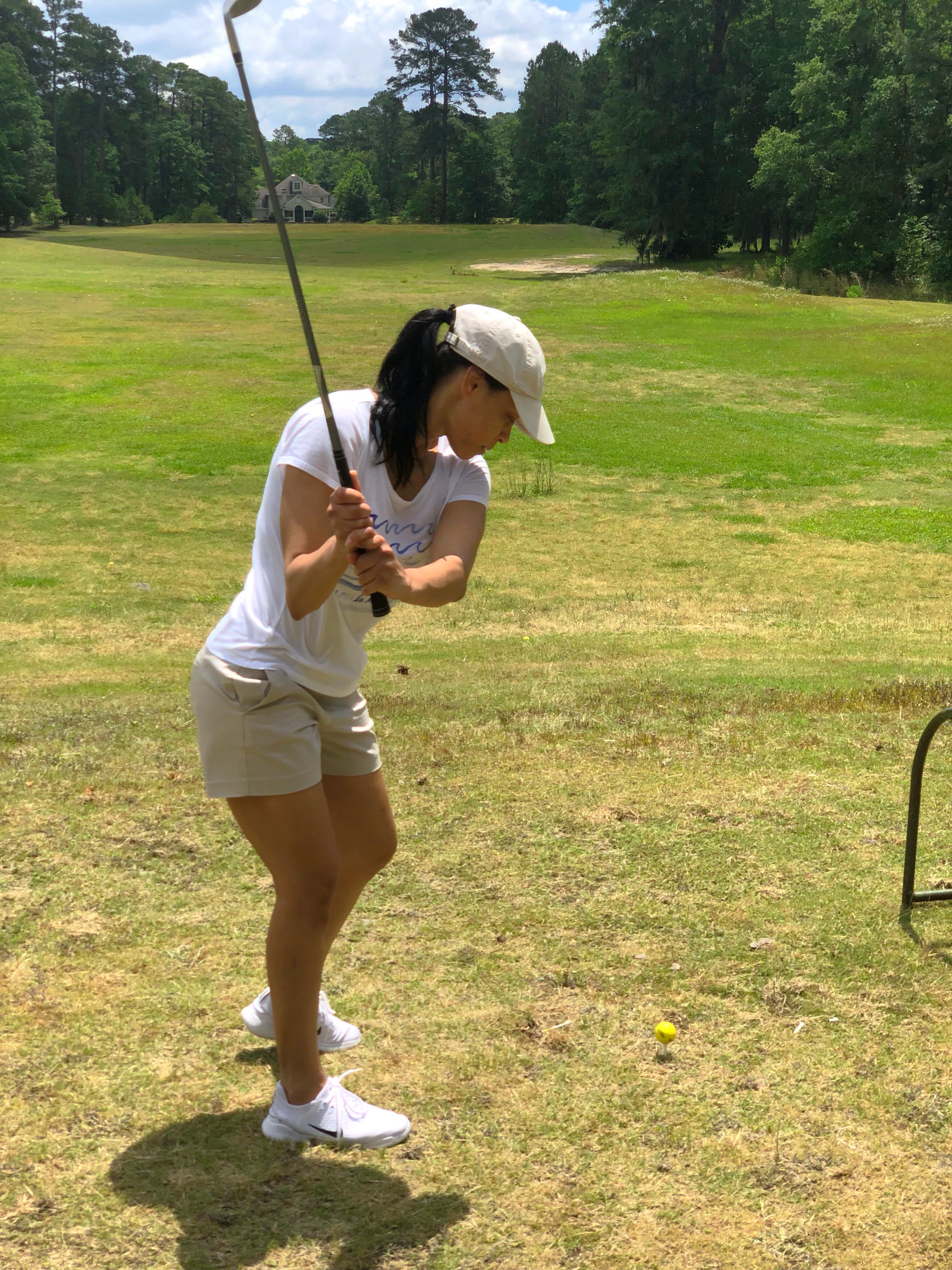 A woman in white shirt holding golf club.
