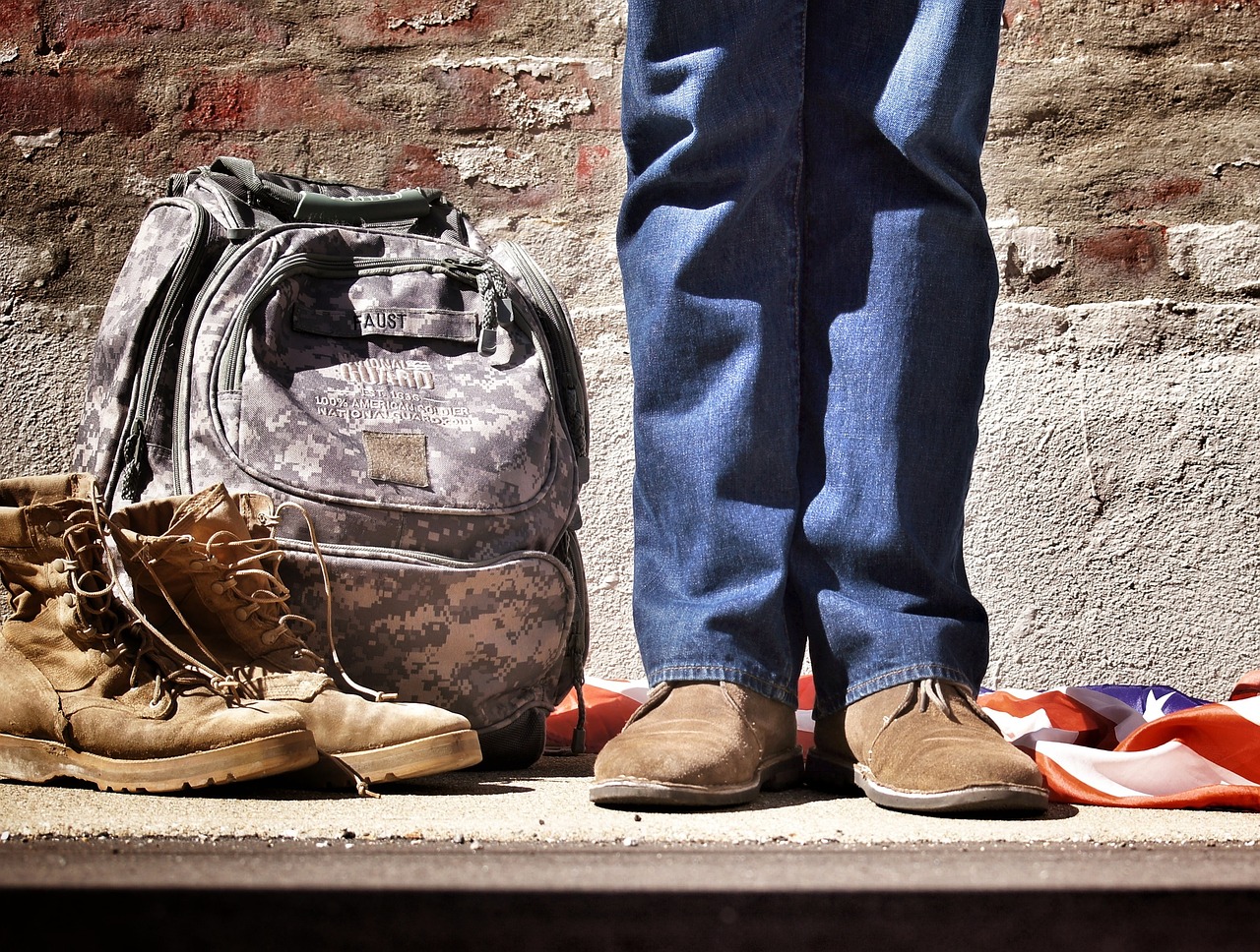A person standing next to a backpack and shoes.