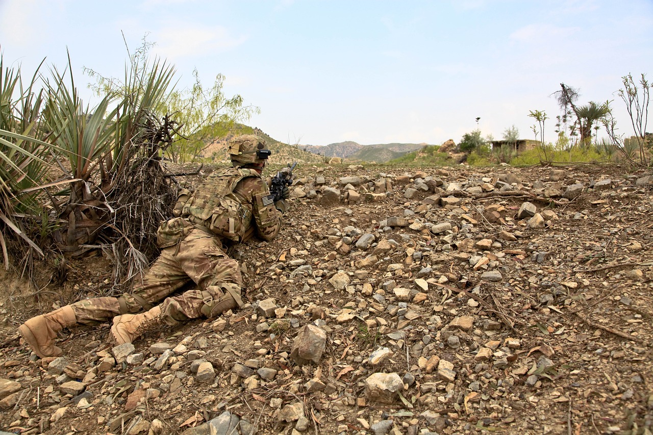 A soldier is sitting on the ground in the desert.