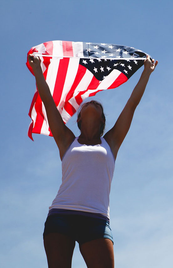 A woman holding an american flag in the air.