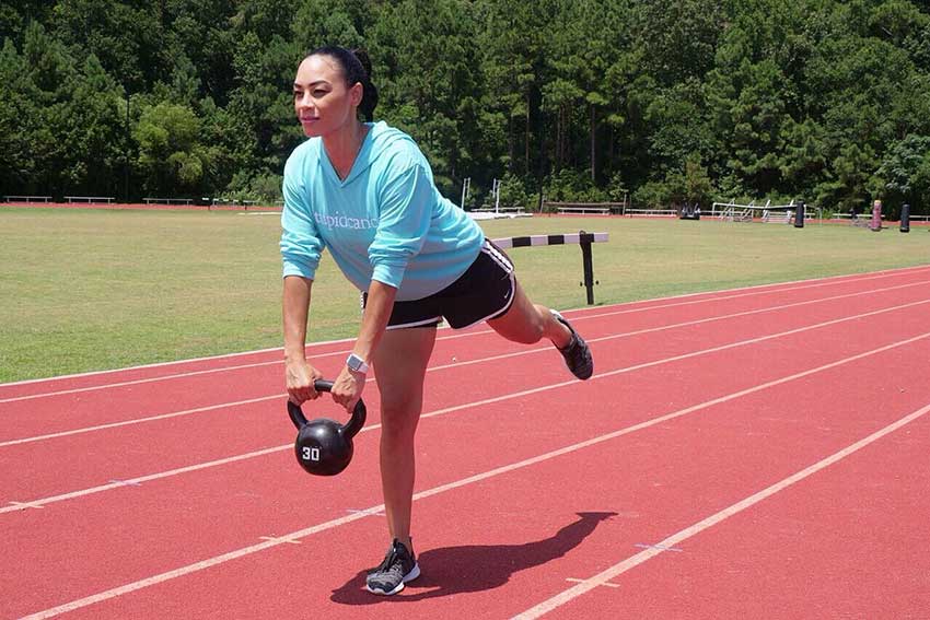 A Woman Is Holding A Kettlebell On The Track